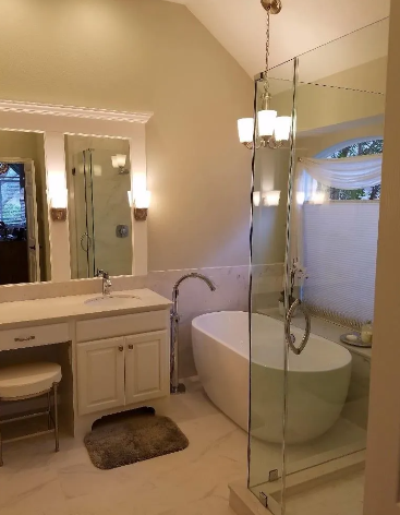 Bathroom with a white freestanding tub, glass shower enclosure, vanity, and neutral walls.