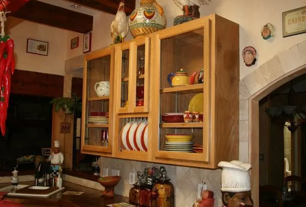 Wooden kitchen cabinets with glass doors, displaying plates and dishes.