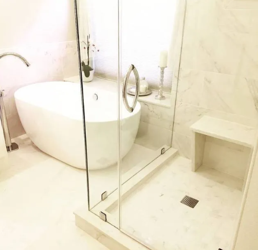 A luxurious white bathroom with a freestanding tub, glass shower, and marble accents.