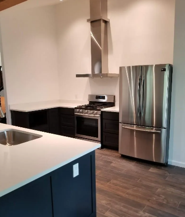 Modern kitchen with dark cabinets, stainless steel appliances, and white countertops.