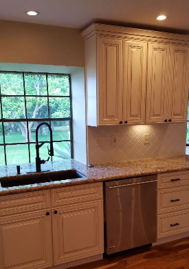 Kitchen with white cabinets, stainless steel appliances, and granite countertops. A black faucet sits in front of a window.
