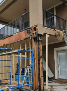 Damaged exterior column supporting a balcony; wood rot visible. Brown, beige, and black colors. Scaffolding is present.