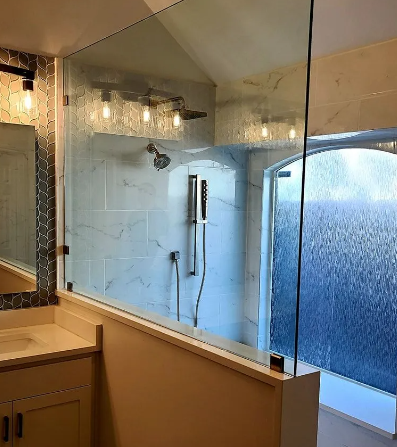 Bathroom with glass shower enclosure, white tile, vanity with sink, and light fixtures.