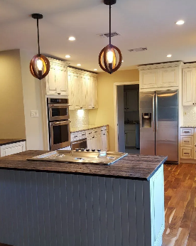 Kitchen with white cabinets, stainless steel appliances, and island with pendant lights.