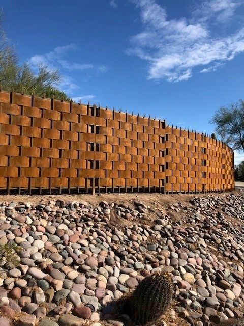 a basket weave fence is surrounded by rocks and a cactus