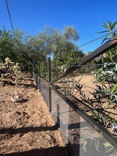 a fence with a cactus in the background and a blue sky