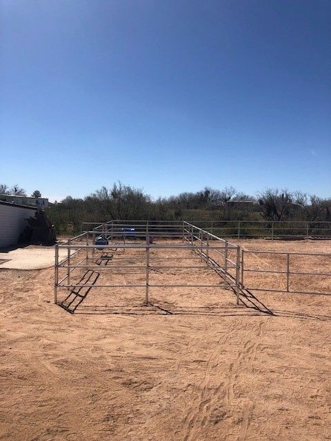 there is a fence in the middle of a dirt field