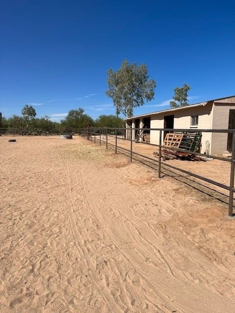 a dirt field with a fence and a building in the background