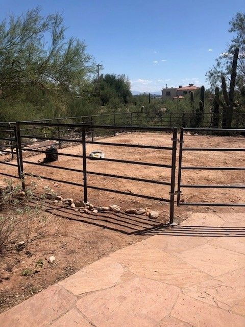 a fence with a gate in the middle of a dirt field