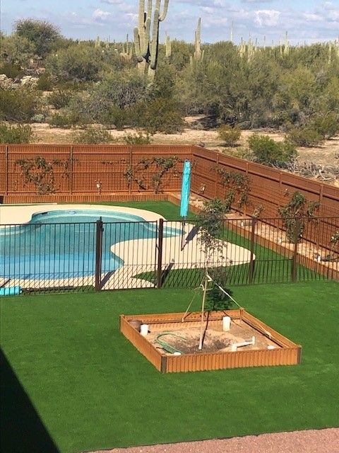 a fenced in backyard with a swimming pool and a sandbox