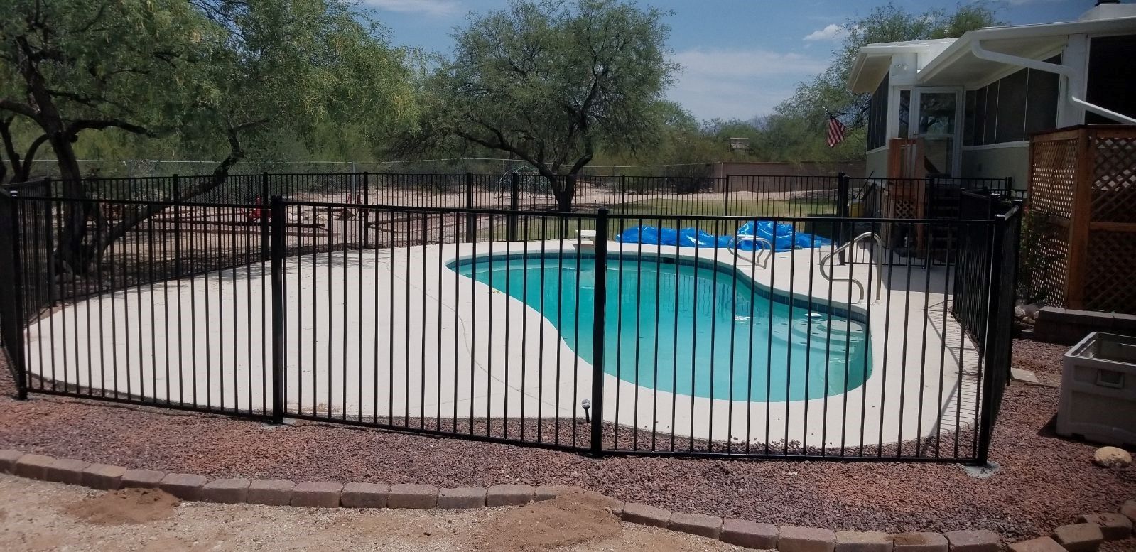 a fence surrounds a large swimming pool in a backyard