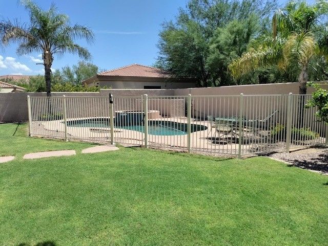a fence surrounds a swimming pool in a backyard