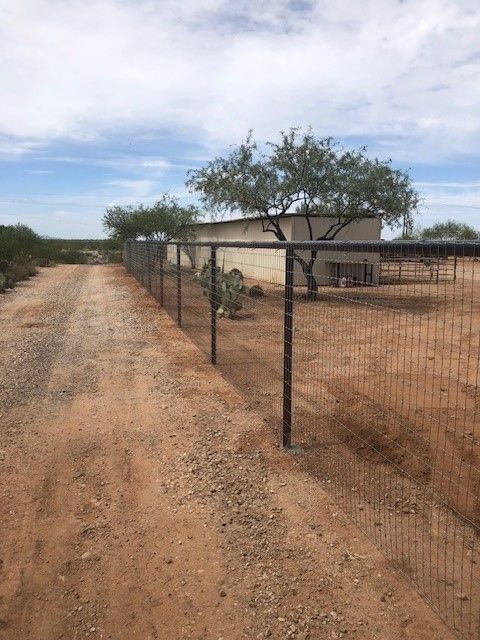 a dirt road with a fence along the side of it