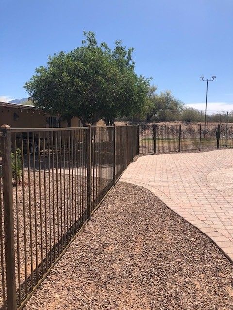 a metal fence surrounds a dirt path leading to a house .