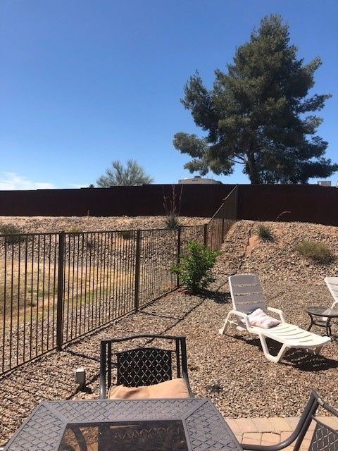 a fenced in backyard with chairs and a table