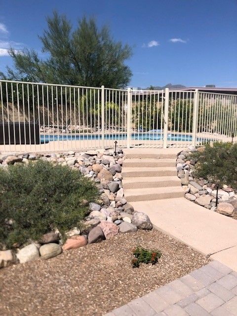 a metal fence surrounds a swimming pool with stairs leading to it