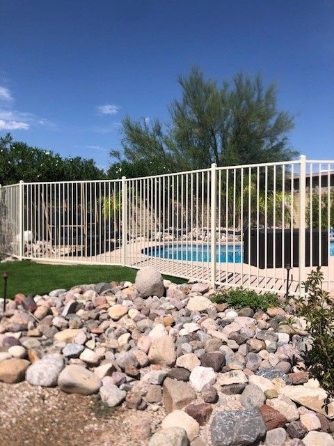 a white fence surrounds a swimming pool in a backyard