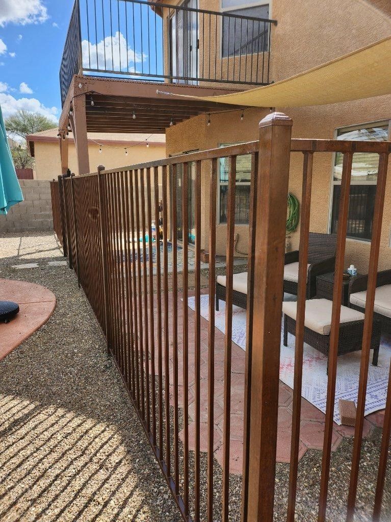 a metal fence surrounds a patio area with furniture and umbrellas