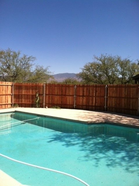 a large swimming pool with a wooden fence surrounding it