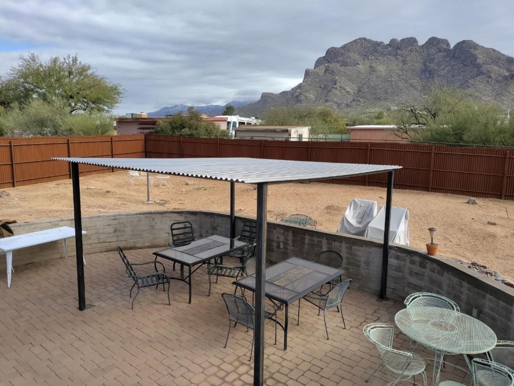 a patio with tables and chairs under a canopy with a mountain in the background