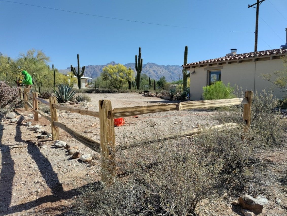 a wooden fence in the desert with a house in the background