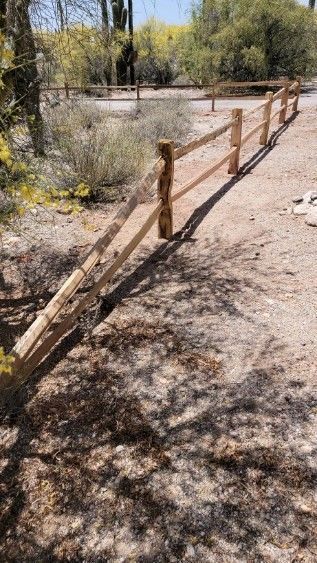 a wooden fence is sitting in the middle of a dirt field