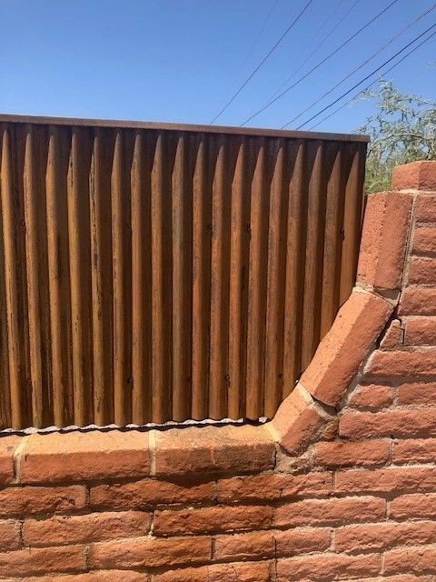 a wooden fence is sitting on top of a brick wall
