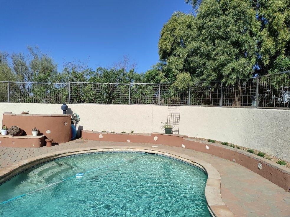 a large swimming pool is surrounded by a fence and trees