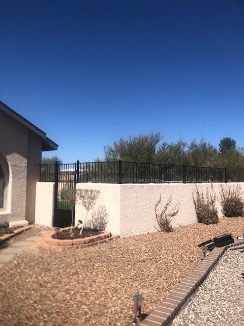 a house with a fence around it and a lot of gravel in front of it