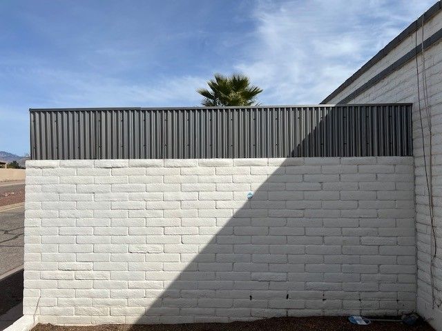 a white brick wall with a metal fence on top of it