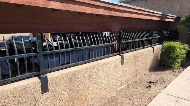 a metal fence is surrounding a concrete wall