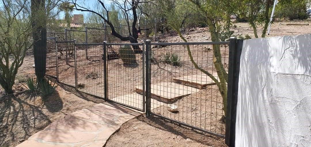 a metal fence surrounds a dirt path in the desert