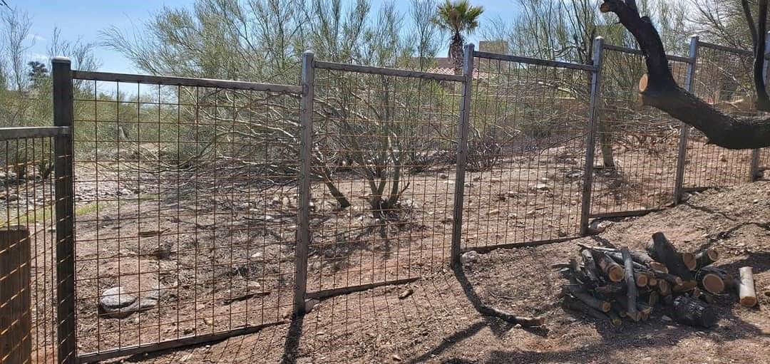 a fence in the middle of a field with a tree in the background