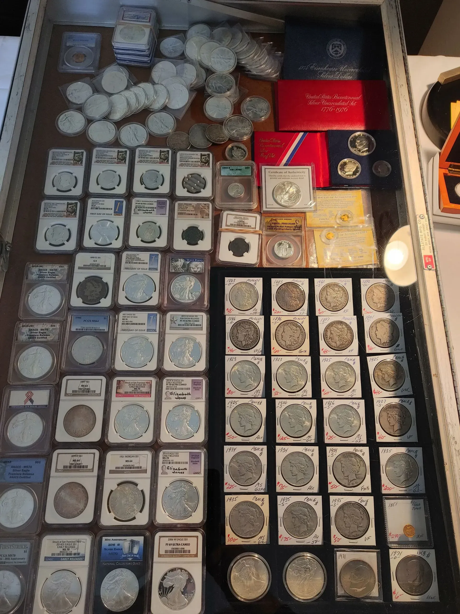 Coins displayed in a glass case, organized in rows and stacks. Silver and red tones dominate.