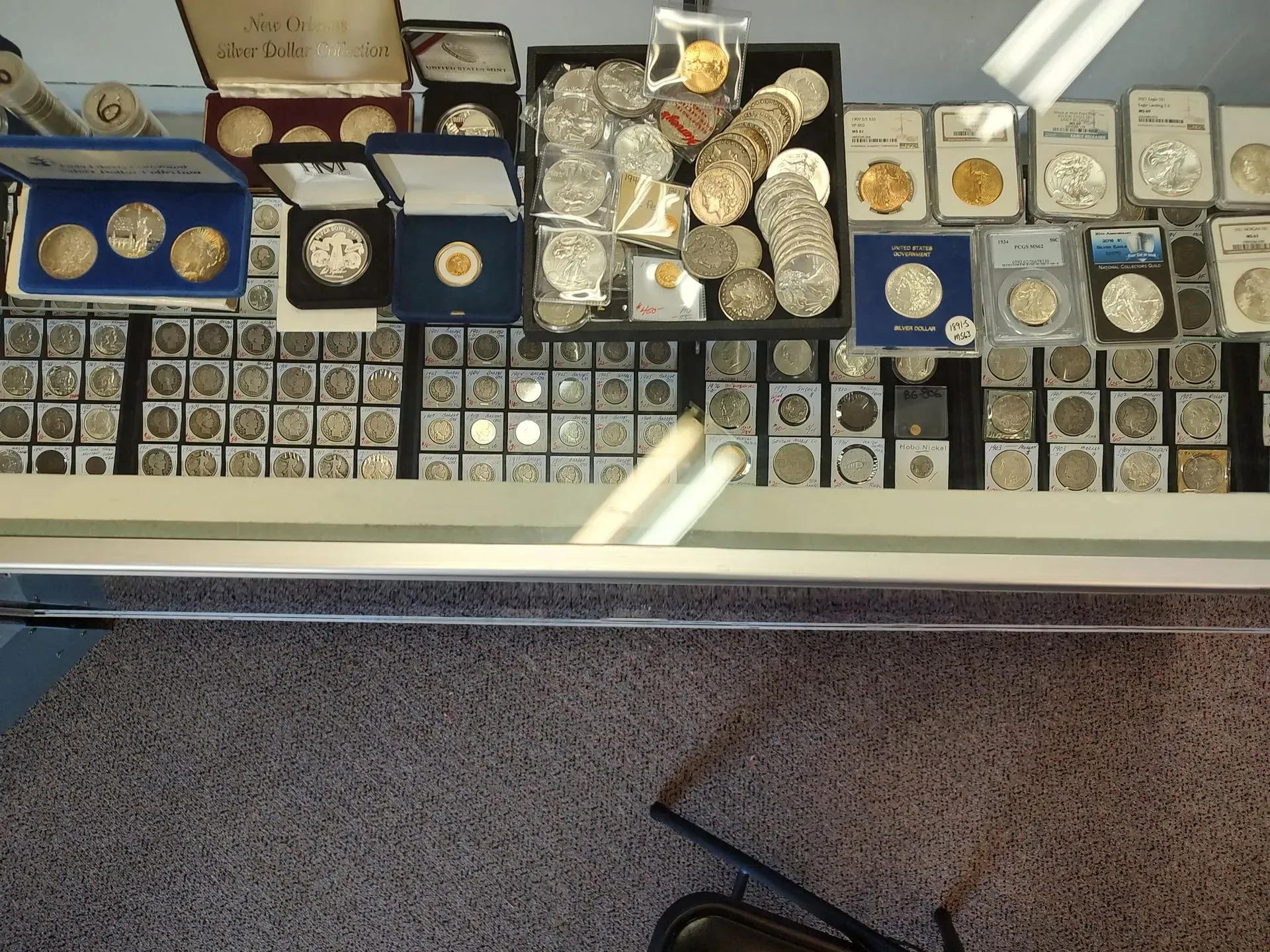 Coins displayed on a table in a shop. Various coins in cases and holders, many silver.