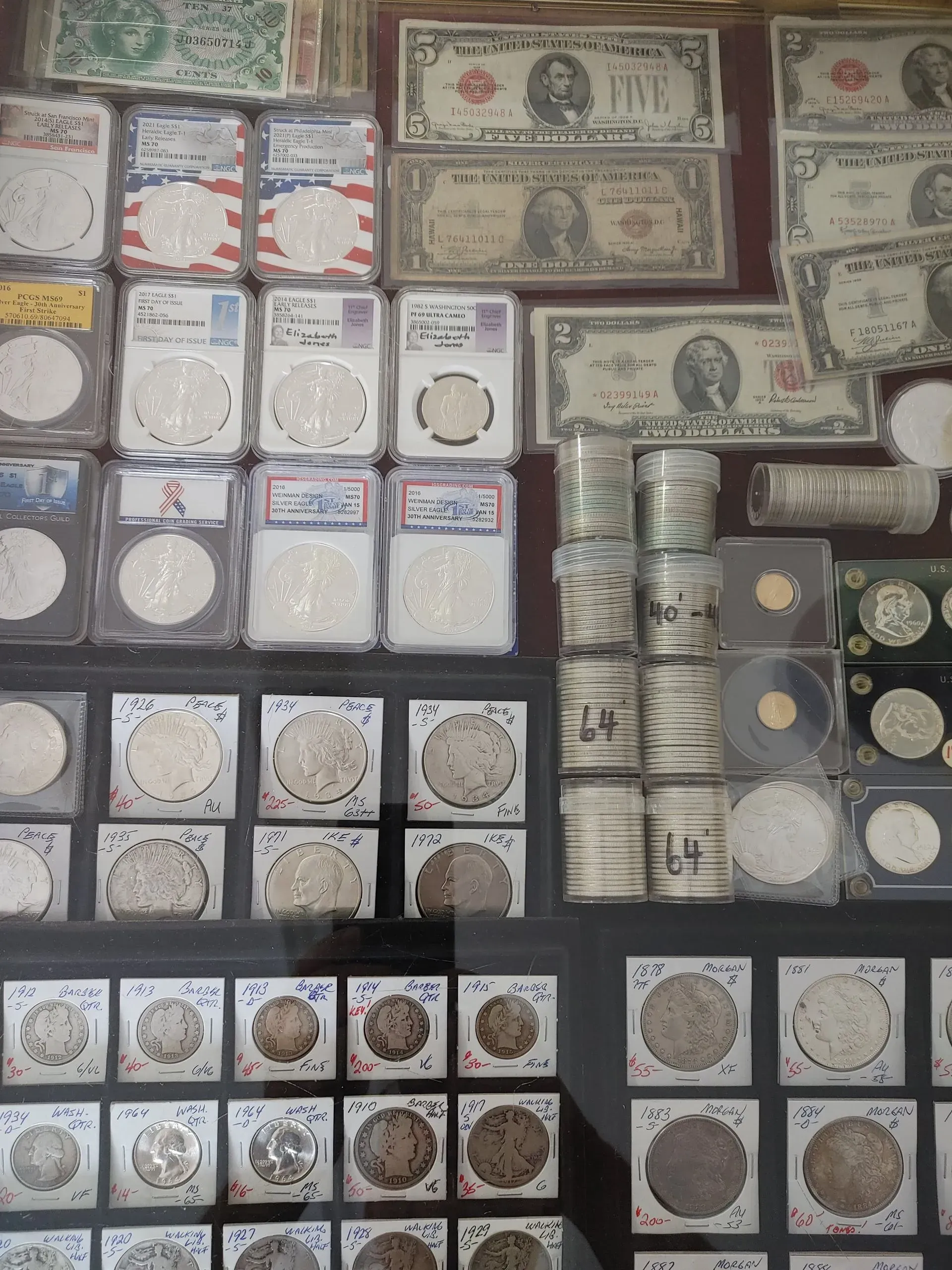Collection of old coins and paper money displayed in a glass case.