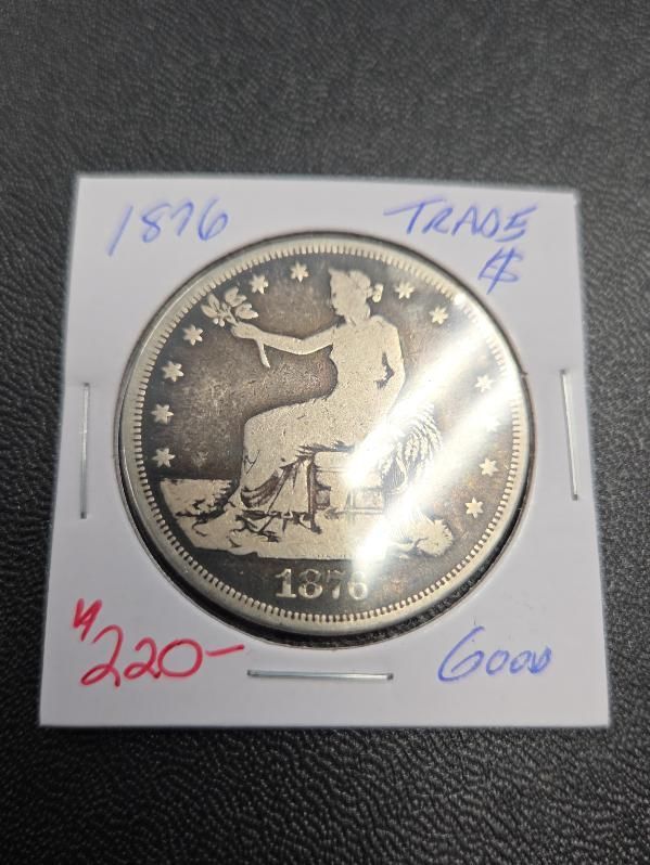 Silver coin in a protective sleeve, showing a seated figure with stars and handwritten notes around it.