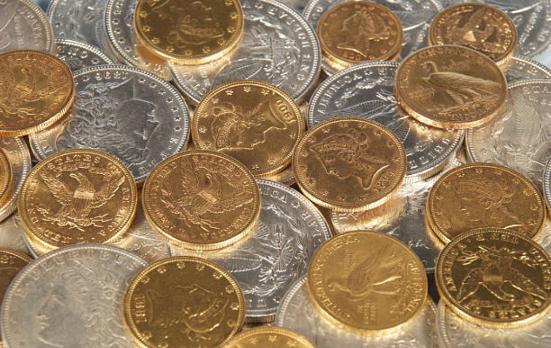 A collection of assorted gold and silver coins piled together, showing intricate patterns and metallic textures.