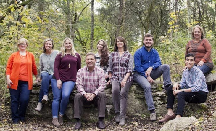 A group of people are posing for a picture in the woods.