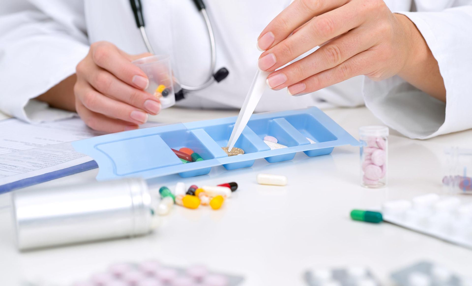 A doctor is taking a pill out of a pill tray.