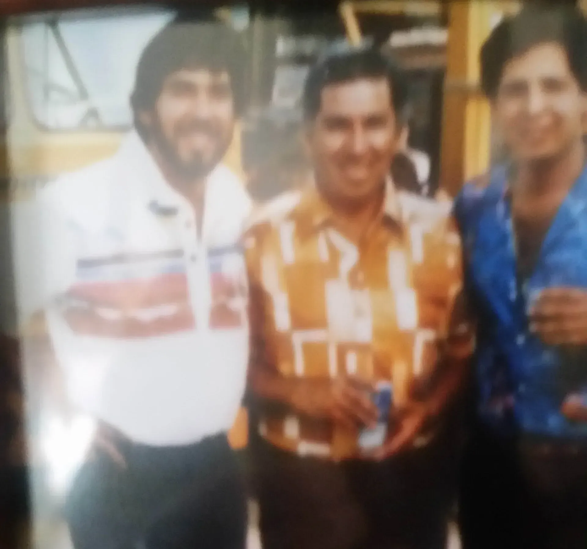 Three men posing for a picture with one wearing a blue shirt