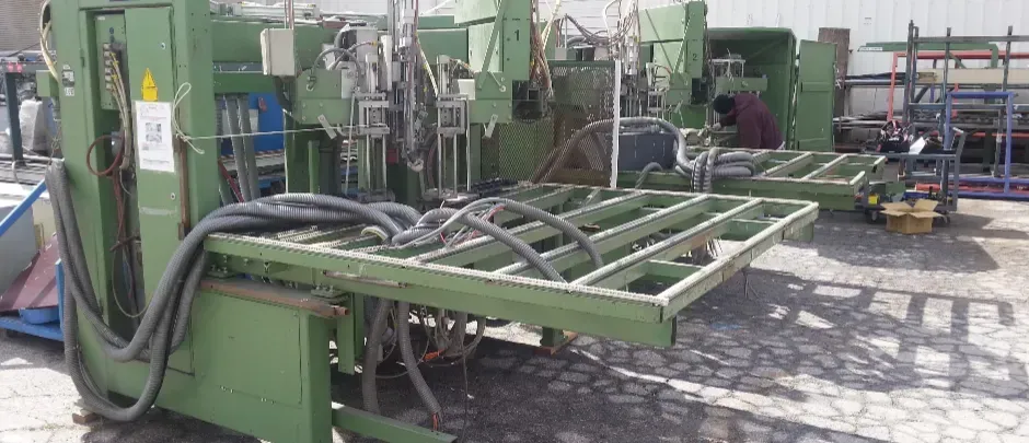 A green machine is sitting in a parking lot next to a building.