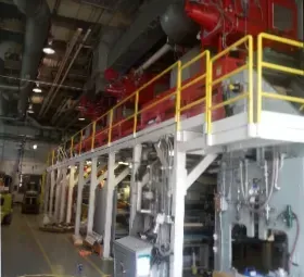 A large factory with a lot of machinery and a yellow railing.