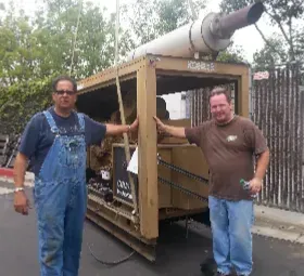 Two men are standing in front of a kobelco generator