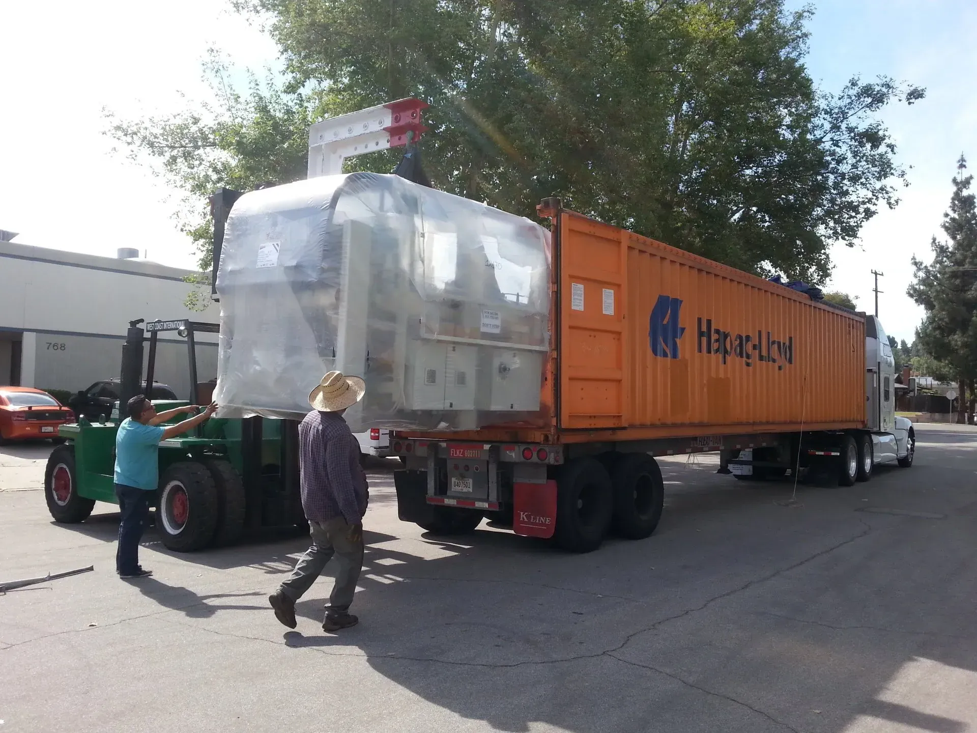 A forklift is carrying a large container that says ' hong kong ' on it