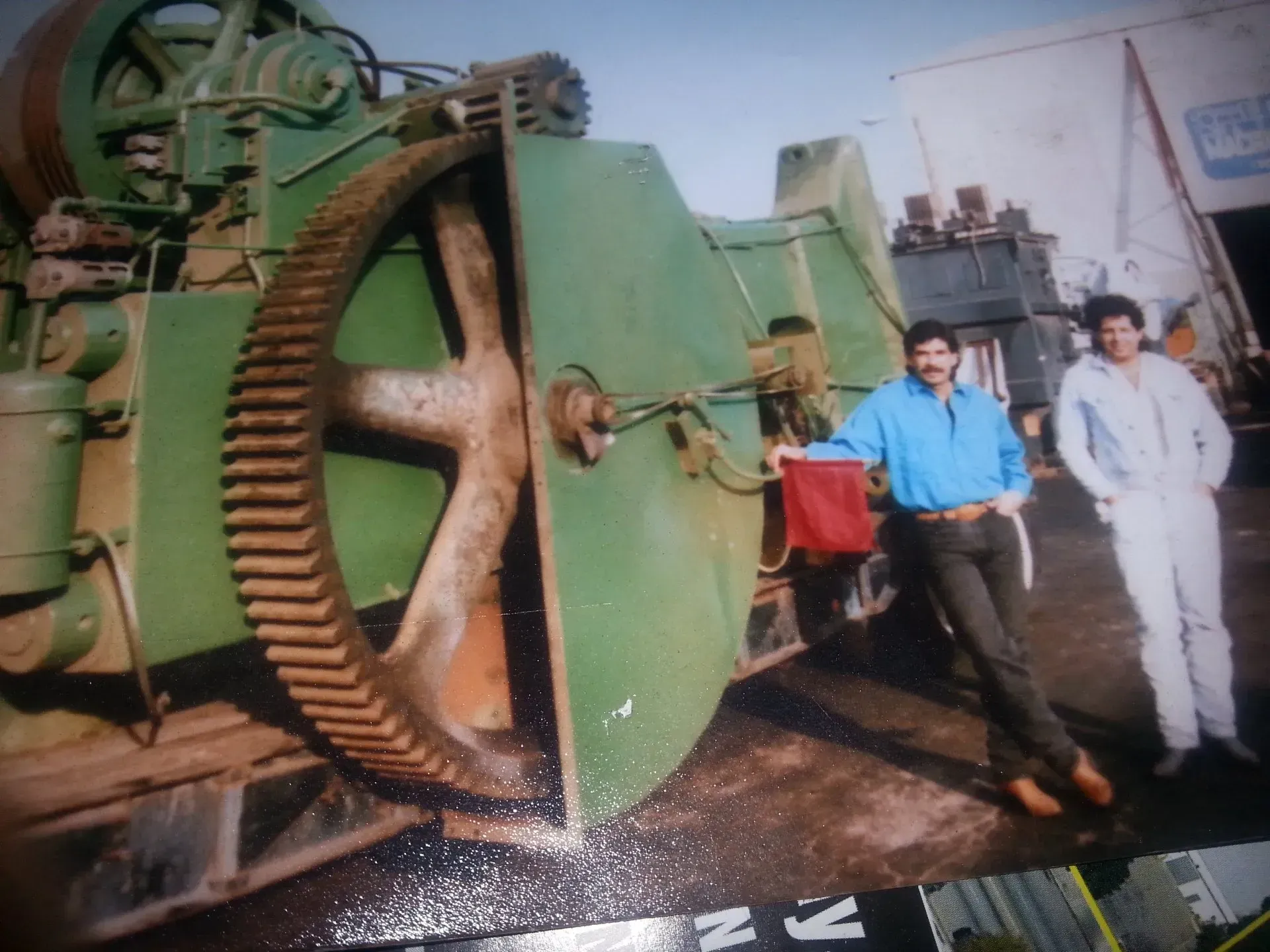 Two men are standing in front of a large green machine
