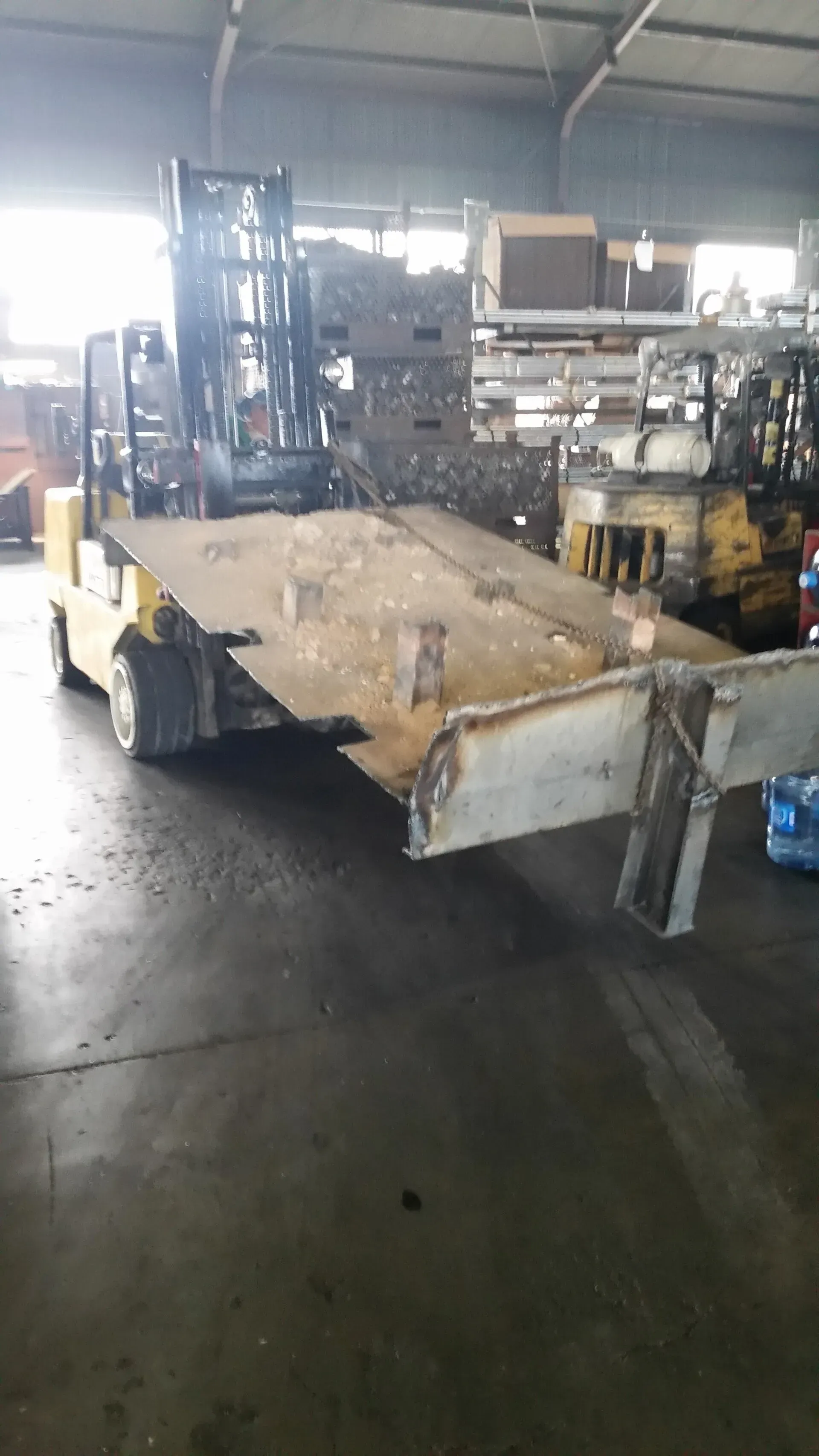 A forklift is driving a flatbed trailer in a warehouse.