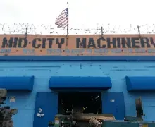A blue building with a sign that says mid city machinery on it.