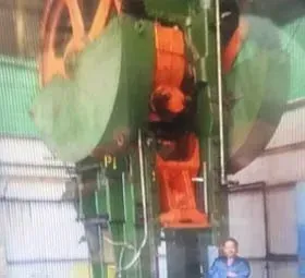 A man is standing in front of a large machine in a factory.