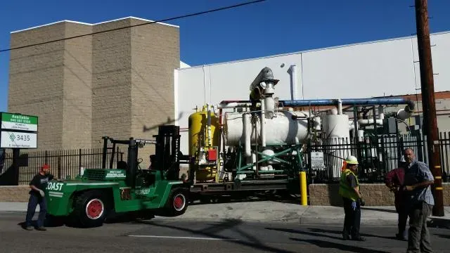 A green forklift is parked in front of a large building